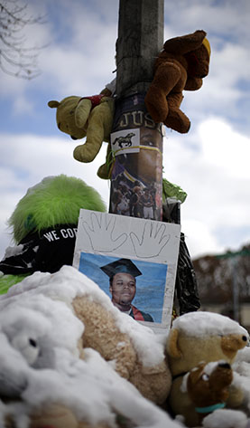 A high school graduation photo of Michael Brown rests on top of a snow-covered memorial Monday, Nov. 17, 2014, more than three months after the black teen was shot and killed nearby by a white policeman in Ferguson, Mo. The shooting sparked weeks of violent protests and  Missouri Governor Jay Nixon declaring a state of emergency today as a grand jury deliberates on whether to charge Ferguson police officer Darren Wilson in the death.